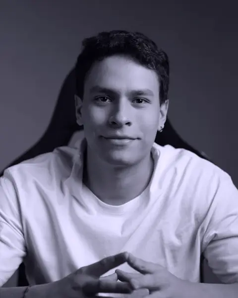 Retrato de Santiago Guillén: sentado, con camiseta clara y las manos juntas.